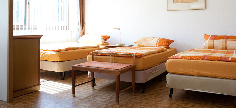 Dreibettzimmer mit orangefarbener Bettwäsche